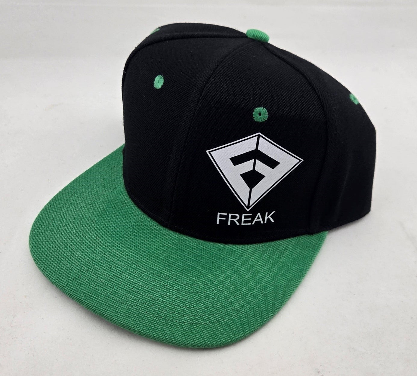 Casquette de type Snapback de couleur noire avec la visière verte claire et le logo Freak Traction blanc - CM Surfing